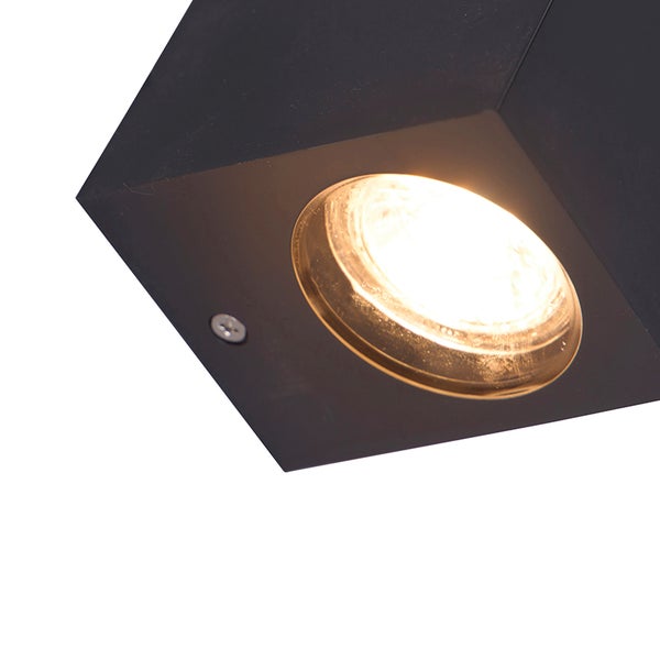 Detailansicht einer quadratischen Wandleuchte in Schwarz mit integriertem Leuchtmittel und warmem Licht.