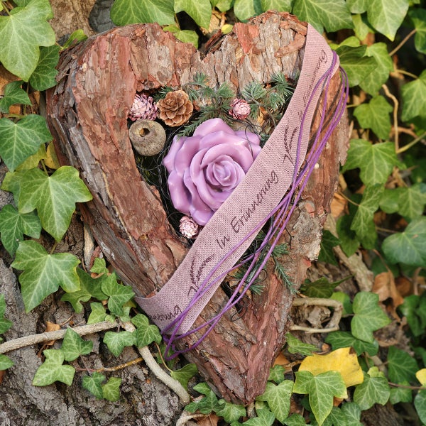 Gedenkdekoration in Herzform aus Baumrinde mit Rose, Tannenzapfen und Trauerband