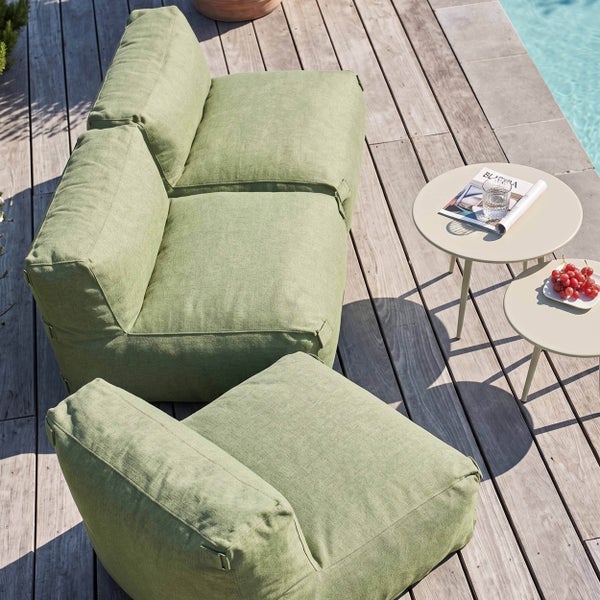 Moderne grüne Gartenlounge aus Stoff auf einer Holzterrasse am Pool mit zwei kleinen Beistelltischen.