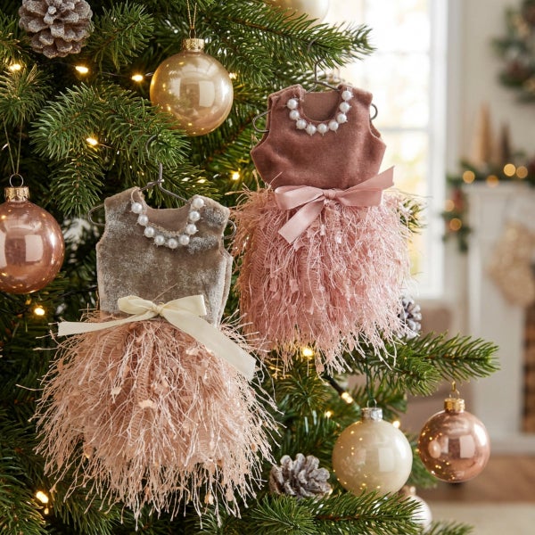 Zwei dekorative Anhänger in Kleidform als Weihnachtsbaumschmuck mit Perlenverzierung und Fransenrock am Tannenbaum.