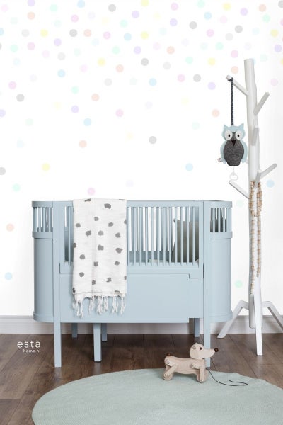 Kinderzimmer mit blauem Babybett, weißem Mobile-Halter in Baumform und Spielzeug