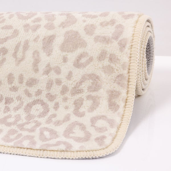 Aufgerollter Teppich mit Leopardenmuster in Creme und Beige und gekettelter Kante.