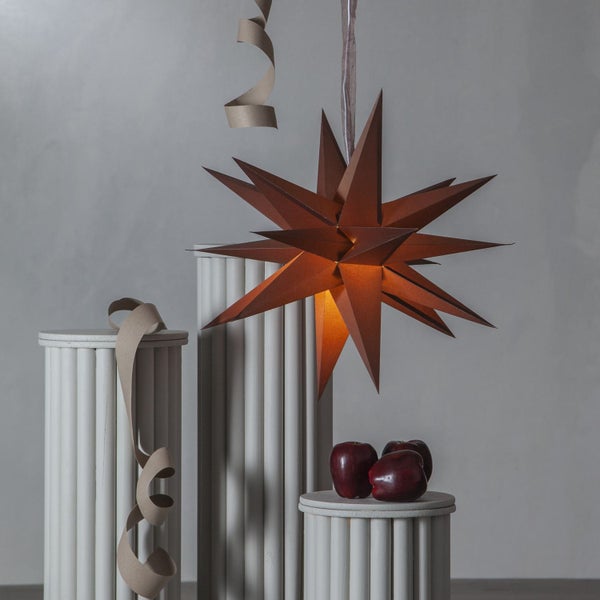 Dekorative Szene mit Sternleuchte, Geschenkbändern und Äpfeln auf Säulen