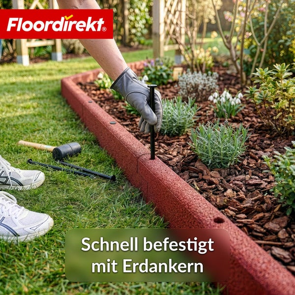 Montage einer roten Rasenkante aus Gummi mit Erdankern im Garten.