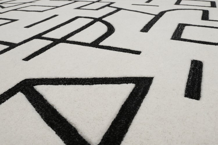 Moderner Teppich mit schwarzem geometrischem Linienmuster auf hellem Grund, Detailansicht der gewebten Struktur.
