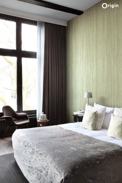 Schlafzimmer mit Bett, Stuhl, Fenster und gemusterter Tapete