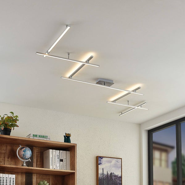 Moderne LED-Deckenleuchte mit linearem, geometrischem Design aus verchromten Stäben in einem hellen Wohnraum.