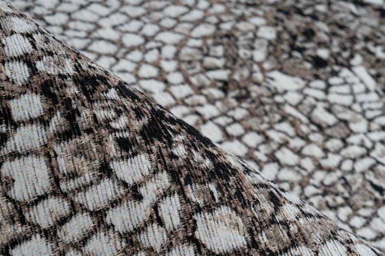 Nahaufnahme eines gewebten Teppichs mit einem strukturierten Mosaikmuster in Schwarz, Braun und Cremeweiß.