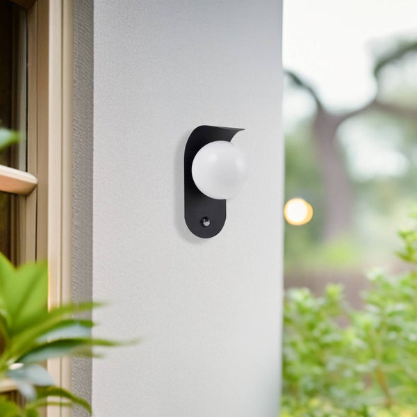 Moderne Außenwandleuchte mit weißer Glaskugel, schwarzer Halterung und Bewegungsmelder an einer Hauswand.