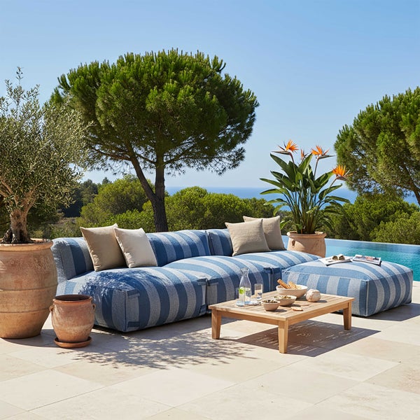 Modernes blau-weiß gestreiftes Outdoor-Ecksofa mit Hocker, Holztisch und Terrakotta-Pflanzgefäßen auf einer Terrasse mit Pool.