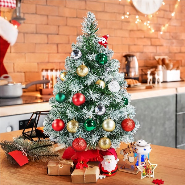 Dekorierter, kleiner Weihnachtsbaum auf einem Tisch mit Geschenken und Dekorationen im Küchenambiente.