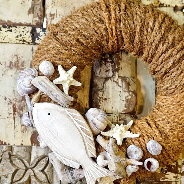 Dekorativer Türkranz mit Seil, Muscheln, Seesternen, Treibholz und Holzfisch