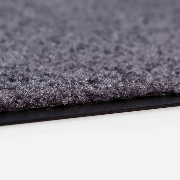 Detailaufnahme einer grauen Fußmatte mit Gummirand.