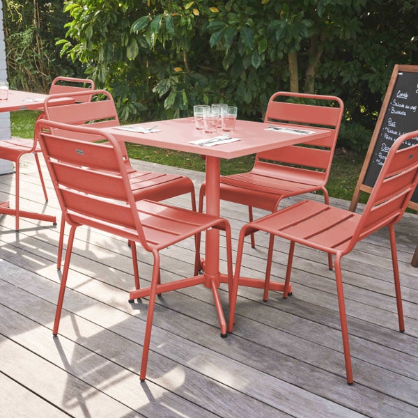 Modernes Gartenmöbel-Set aus Metall mit quadratischem Tisch und vier Stapelstühlen auf einer Holzterrasse in einer hellen, organisierten Gartenumgebung.
