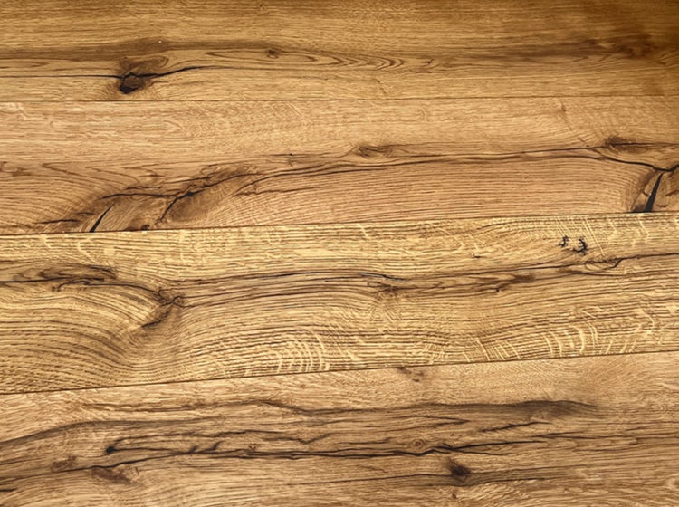Holzboden in Eichenoptik mit ausgeprägter Maserung, Astlöchern und dunklen Rissen.