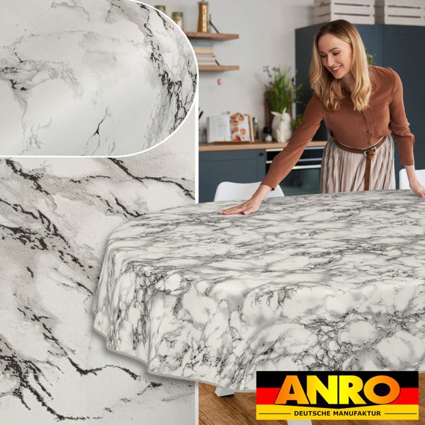 Frau drapiert Tischdecke mit Marmorierung auf Tisch in Küche. Anro Deutsche Manufaktur Logo.