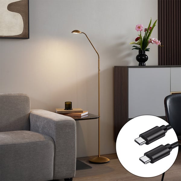 Moderne Stehleuchte aus Metall mit integriertem Ablagetisch und USB-Anschluss neben einem Sofa in einem Wohnzimmer.