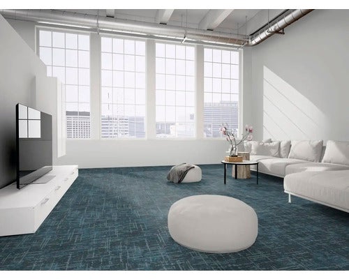 Moderner Wohnbereich im Loft-Stil mit blauem Teppichboden in Musteroptik, weißem Sofa, TV-Lowboard und großen Fenstern.