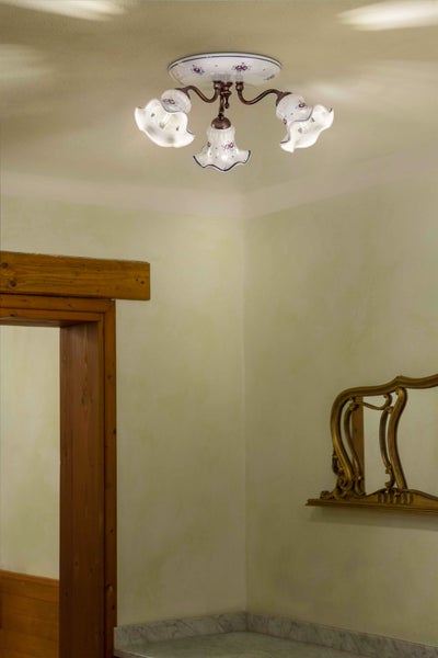 Deckenleuchte mit drei Leuchtenarmen und floralem Dekor in einem hellen Raum.