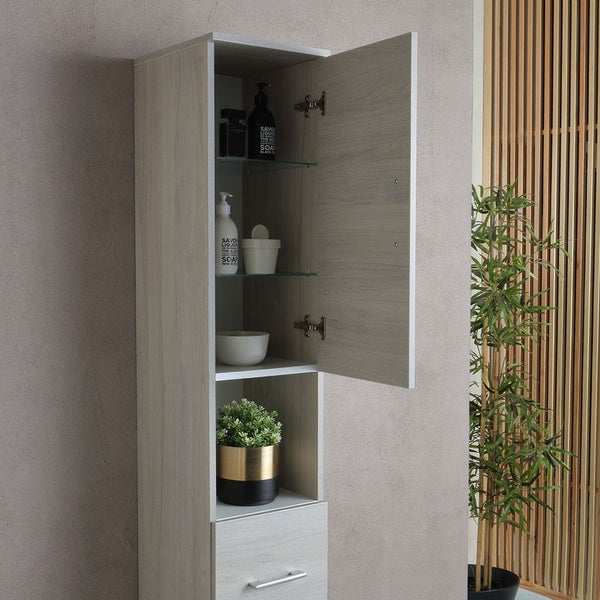 Hoher Badezimmerschrank mit einer offenen Ablage, einer Tür mit Glaseinlegeböden und einem Auszug in Holzoptik.