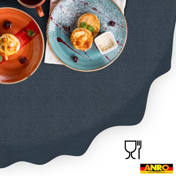 Strukturierte, dunkelgraue Tischdecke, gedeckt mit Tellern und Speisen. Lebensmittelecht. ANRO Logo.