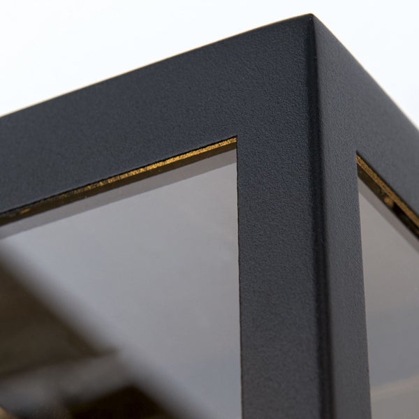 Detailansicht einer Ecke einer Außenleuchte aus strukturiertem Metall mit Glaseinsatz und goldfarbenem Akzent.