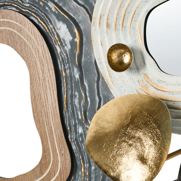 Detailansicht einer Wanddekoration mit Holzoptik, strukturierten Oberflächen in Grau und Weiß sowie goldenen Metallelementen.