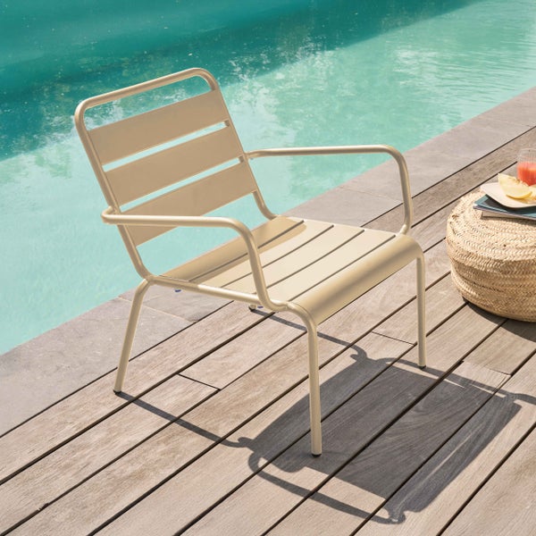 Beigefarbener Garten-Loungesessel aus Metall mit Latten-Design auf einer Holzterrasse am Pool.