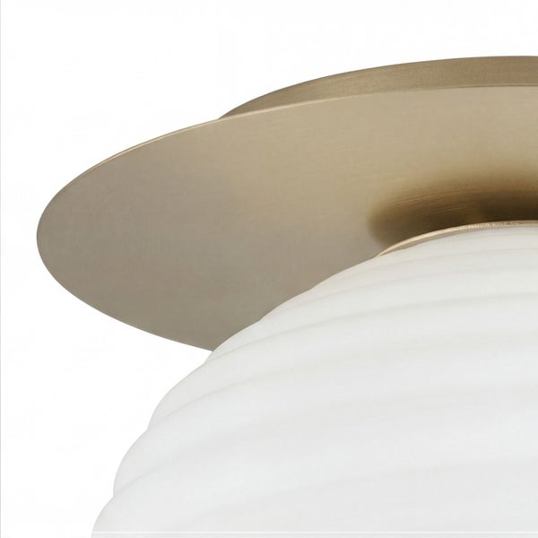 Nahaufnahme einer Deckenleuchte mit goldfarbener Metallhalterung und weißem geriffeltem Glasschirm.