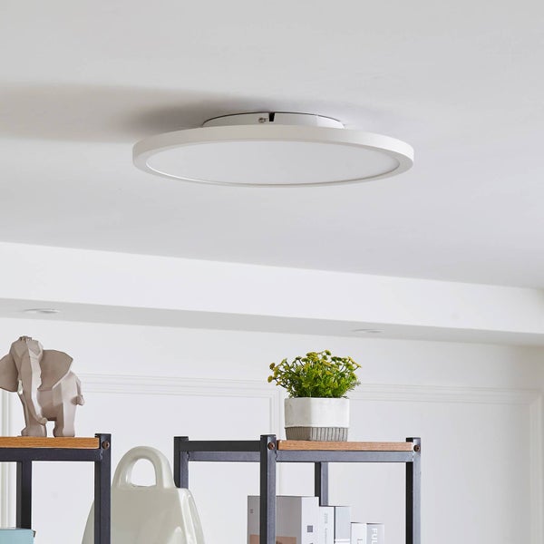 Runde flache LED-Deckenleuchte in Weiß an einer weißen Decke über einem Regal mit Dekoration.