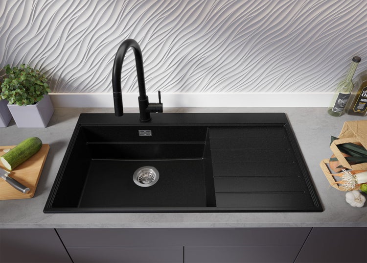 Schwarzes Spülbecken mit Abtropffläche und Armatur auf einer Küchentheke mit Lebensmitteln