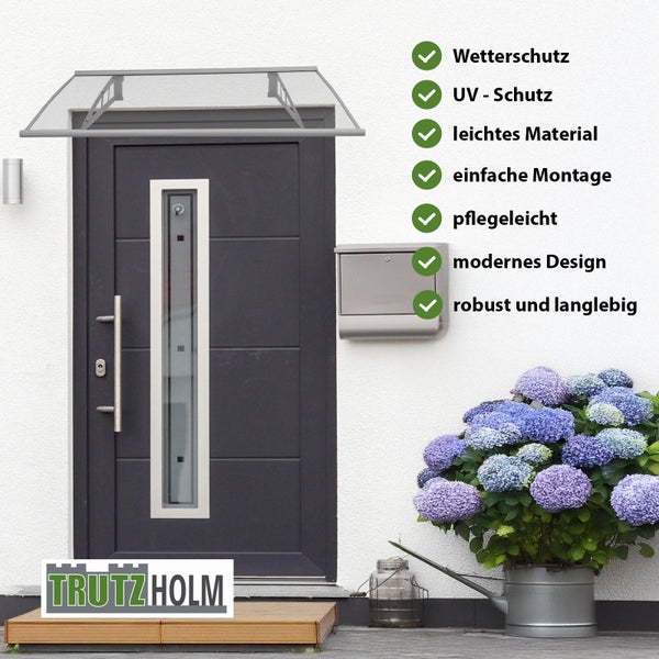 Vordach von Trutzholm mit Liste der Produktvorteile über einer modernen Eingangstür mit Briefkasten und Blumen.