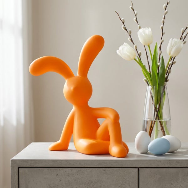 Osterdekoration sitzender Osterhase als dekorative Figur auf einem Tisch mit Blumenvase und Ostereiern als Frühlingsdekoration.