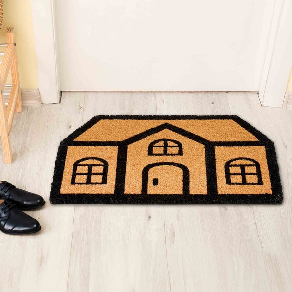 Fußmatte in Hausform mit Tür und Fenstern vor einer Tür