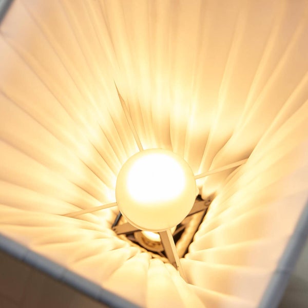 Innenansicht eines quadratischen Lampenschirms mit plissiertem Stoff und leuchtender Glühbirne.