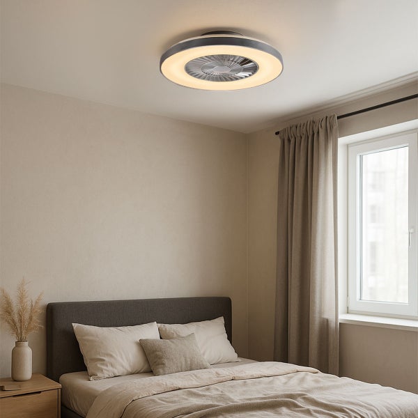 Moderner runder LED-Deckenventilator mit warmweißem Leuchtring in einem hellen, minimalistischen Schlafzimmer über einem Bett.