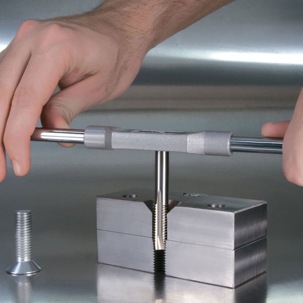 Gewindebohrer im Einsatz mit einer Schraube daneben