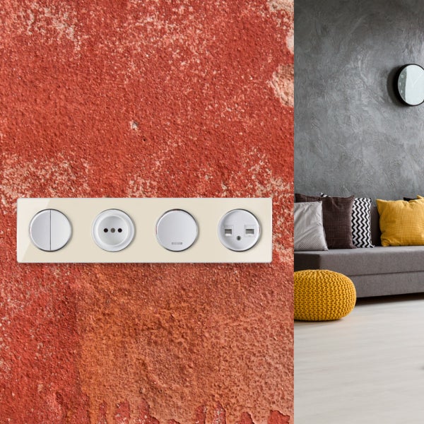 Mehrfachrahmen mit Lichtschalter, Steckdose und Netzwerkdosen an einer strukturierten Wand mit modernem Wohnbereich im Hintergrund.