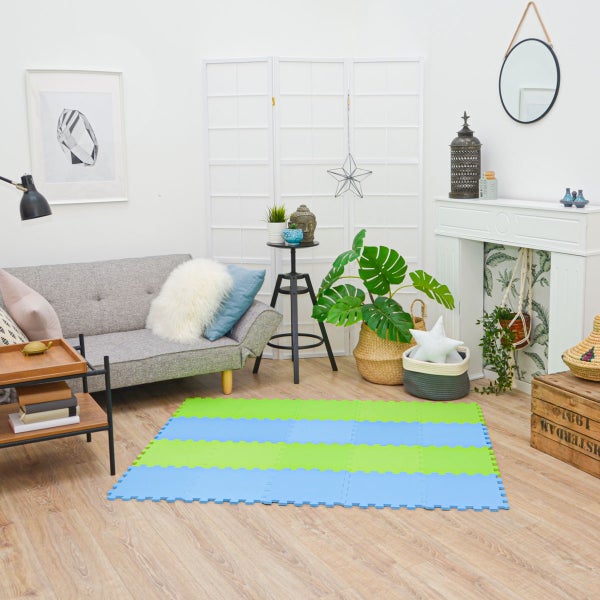 Modernes Wohnzimmer mit grauem Sofa, Zimmerpflanzen und einer blau-grünen Schaumstoff-Puzzlematte auf hellem Holzboden.