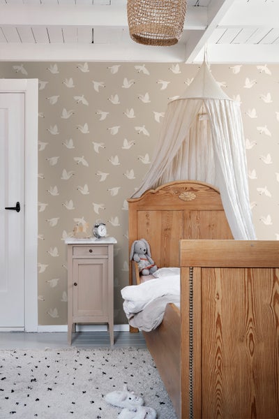 Gemütliches Kinderzimmer mit Holzbett, Nachttisch und Tapete mit Vogelmuster