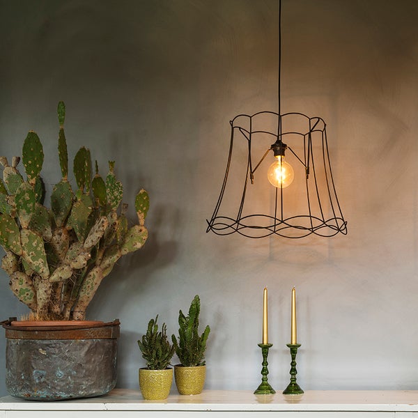 Dekorative Szene mit einer Hängelampe mit Drahtschirm, Kakteen und Kerzenständern