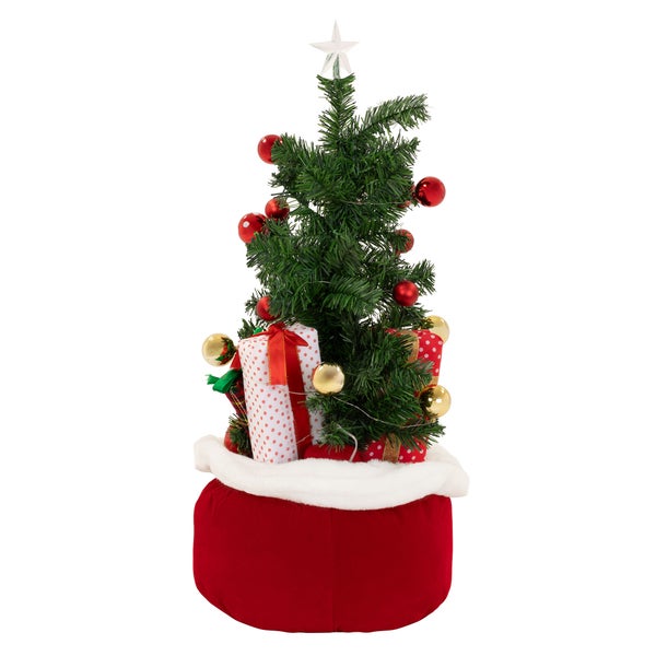 Künstlicher Weihnachtsbaum in einem roten Weihnachtssack mit Kugeln und Geschenken dekoriert