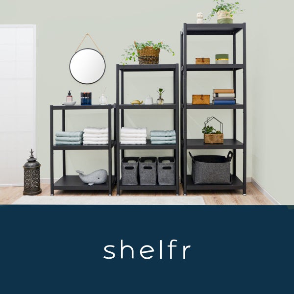 Drei schwarze Metallregale in verschiedenen Höhen mit Handtüchern, Filzkörben und Dekoration in einem hellen Zimmer.
