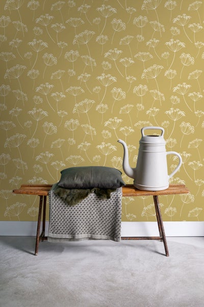 Dekorative Szene mit gemusterter Tapete, Bank, Kissen und Gießkanne.