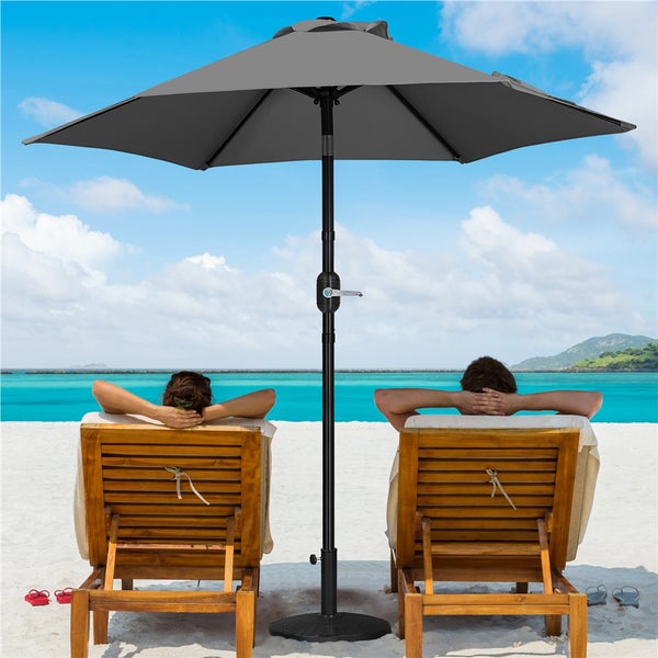 Szene mit zwei Personen, die unter einem Sonnenschirm am Strand in Liegestühlen entspannen