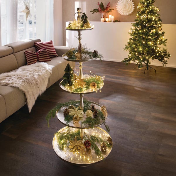 Dekorative vierstöckige Etagere aus Metall mit Weihnachtsdekoration und Lichterkette im festlich geschmückten Wohnzimmer.