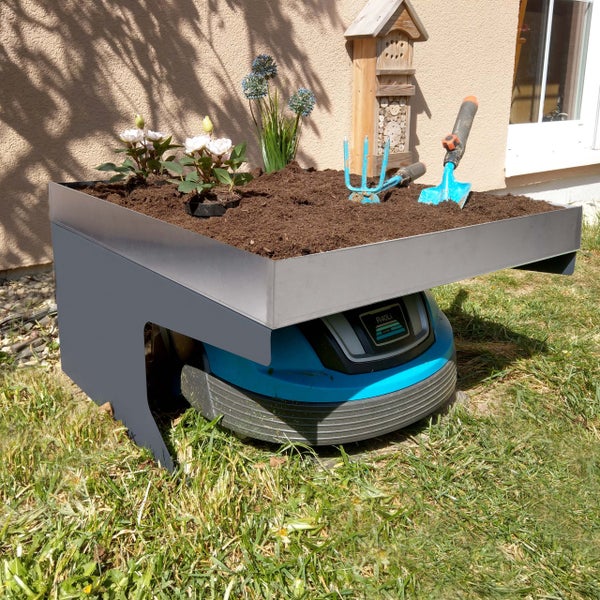 Szene mit einem Rasenmähroboter unter einem Pflanztisch, bepflanzt mit Blumen und Gartengeräten