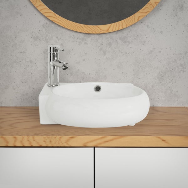 Nahaufnahme einer Wand mit grüner Textiltapete, dekoriert mit einem Tisch mit Pflanzen, Büchern und gerahmten Bildern.