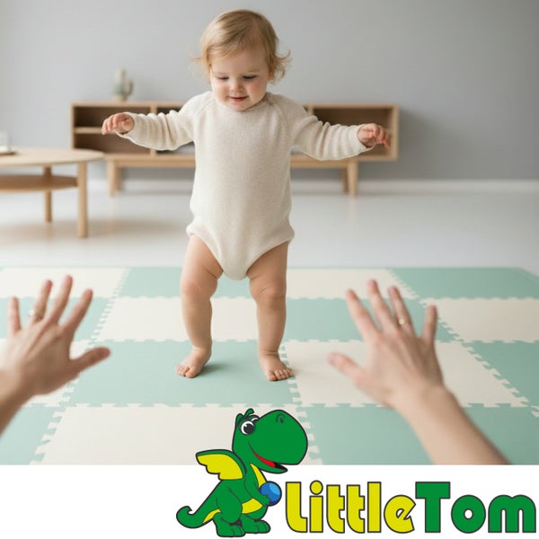 Kleinkind steht auf einer Puzzle-Spielmatte aus Schaumstoff in einem hellen Zimmer, Hände werden dem Kind entgegengestreckt. LittleTom Logo.
