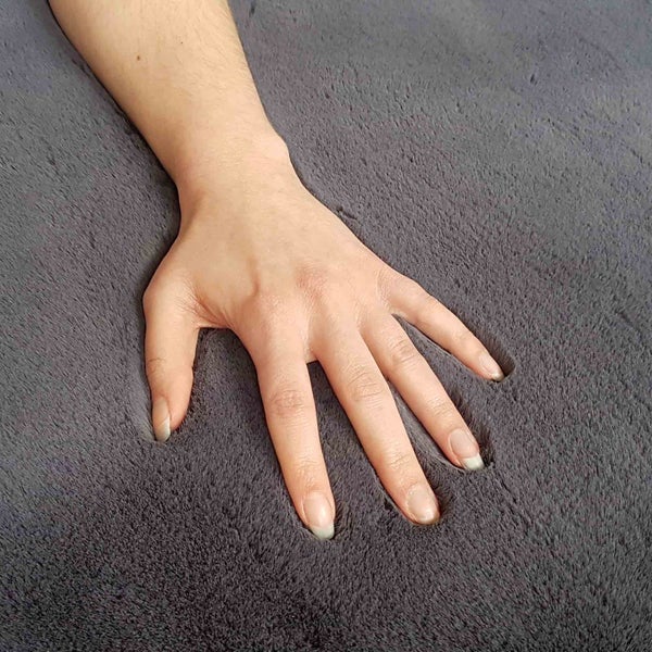 Hand drückt in weichen Teppich